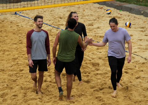 4 Spieler*innen stehen auf einem Beachvolleyballfeld und klatschen sich die Hände ab.