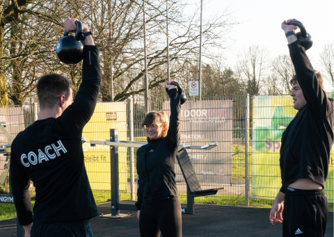 Eine Gruppe von Menschen trainiert am Outdoorgym in Wenderfeld.