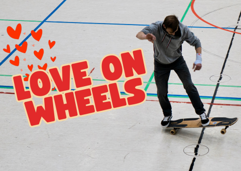 Das Foto zeigt einen Mann, der in einer Sporthalle auf einem Longboard fährt. Über dem Foto liegt der Schriftzug "Love on Wheels".